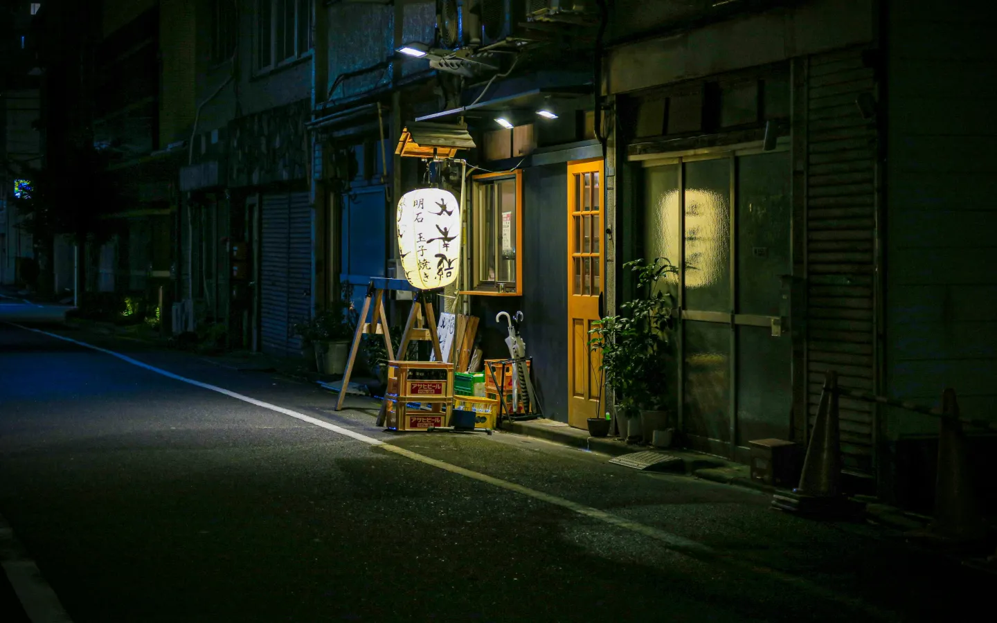 Small dimly lit restaurant on a quiet Tokyo side street at night.